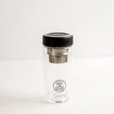 A sleek GEVA Vital Premium Teeflasche mit Edelstahl Teesieb (380ml, SCHWARZ) stands on a white surface with a minimalist background—handlich, auslaufsicher und zeitsparend, ideal für unterwegs.